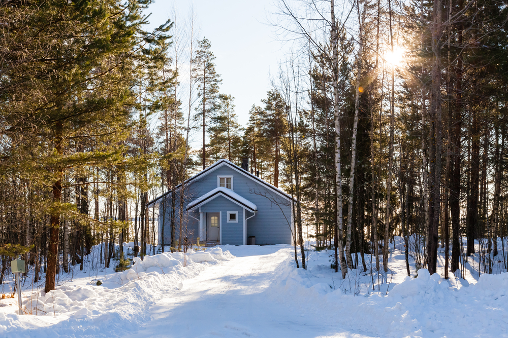 Grey cottage in the middle of a forest in winter.