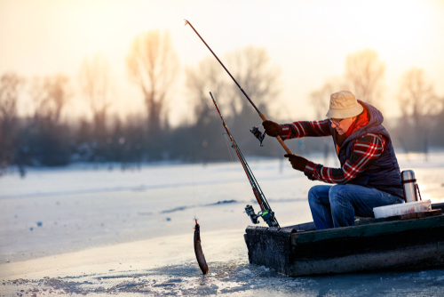 Older man fishing from a boat in the winter.