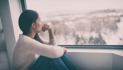 Woman looking out a window at a winter landscape.