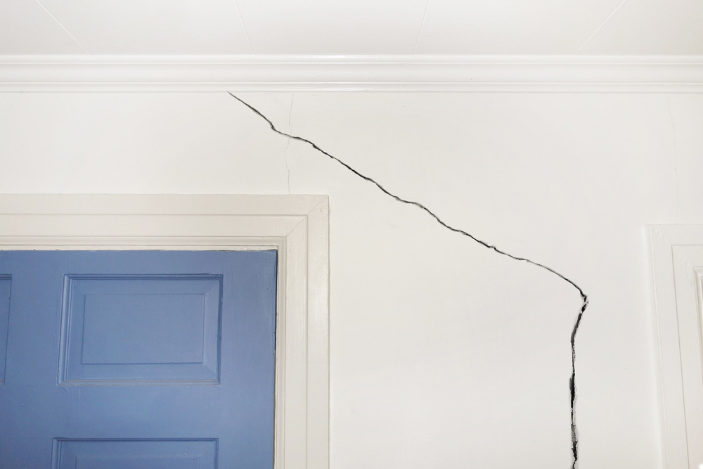 Drywall crack next to a blue door.