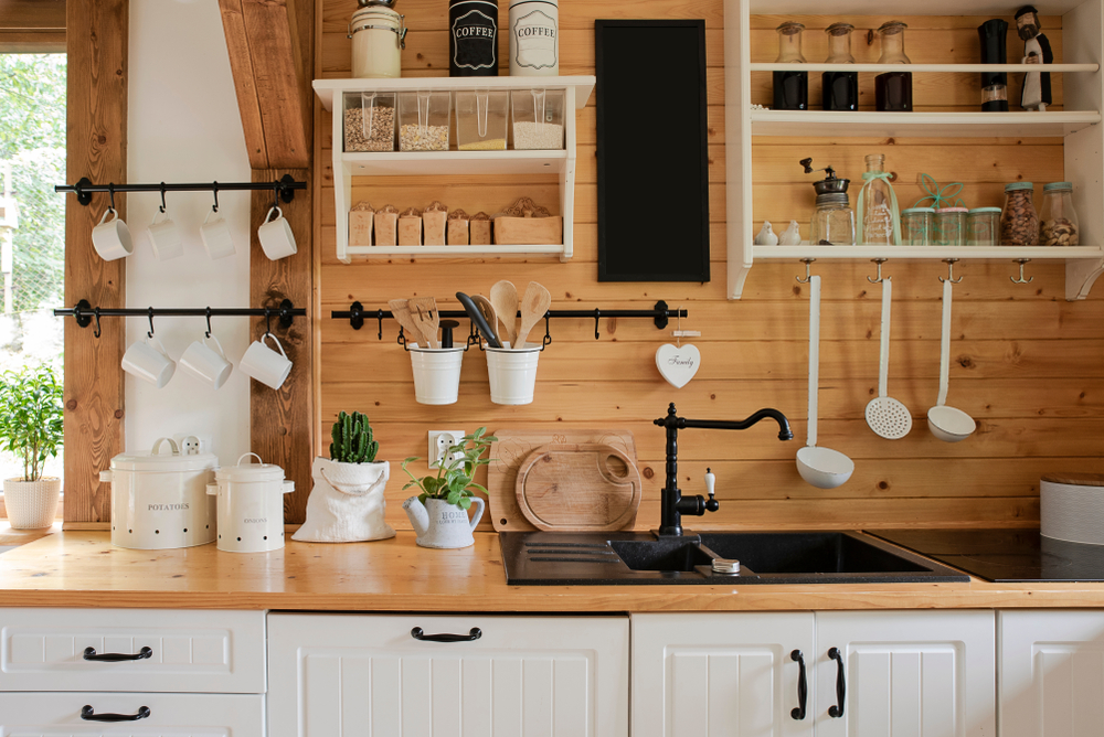 Rustic cottage kitchen with white cabinets and wood countertops and walls.