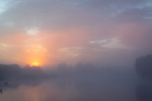 Sunset on a fog-covered lake.