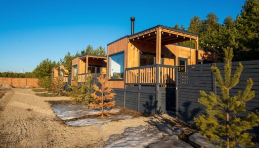Small, wooden cottages or bunkies surrounded by trees and a dark grey fence.