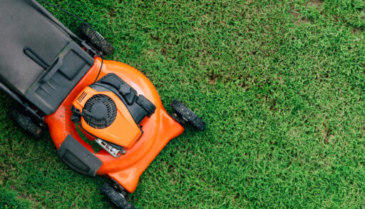 Overhead view of an orange lawnmower on a green lawn.