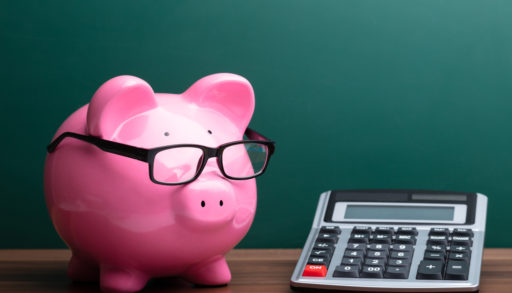 Calculator And Pink Piggybank With Eyeglasses In Front Of Green Board