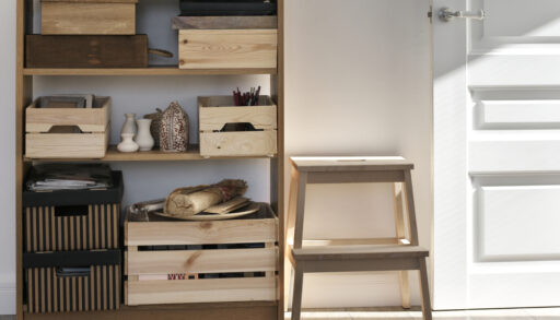 Wooden crates organized on a wood shelf near a step stool and door.