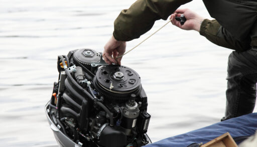 Person adjusting an outboard motor on a boat.