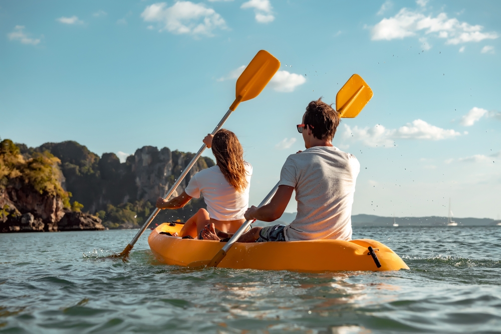 Man and woman paddling a yellow kayak.