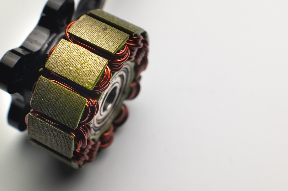 Disassembled brushless motor with gold plates and red wires.