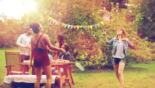 Group of people having an outdoor party and playing badminton.
