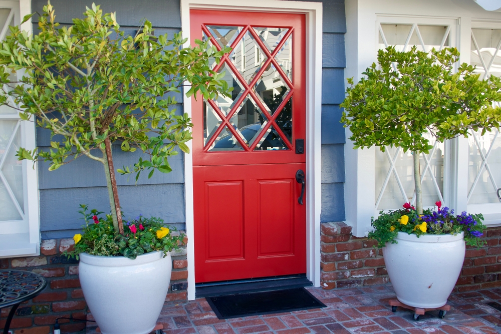 Red front door with two large trees on either side.
