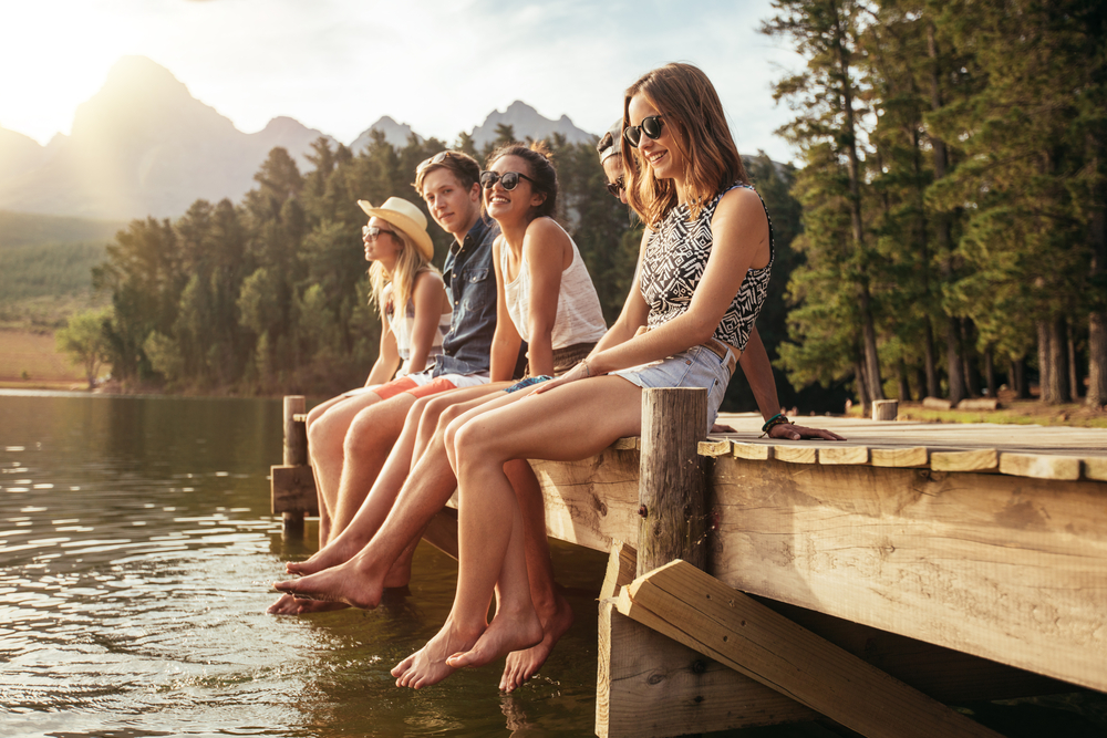 Group of young friends sitting on a dock together.