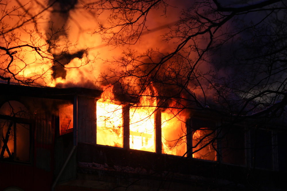 Residential house on fire with flames coming through windows.