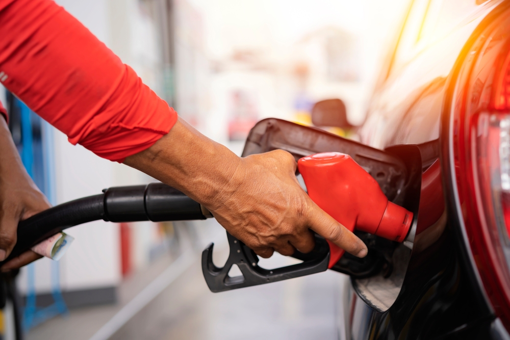 Person using a red-coloured nozzle to fill a car with gas.