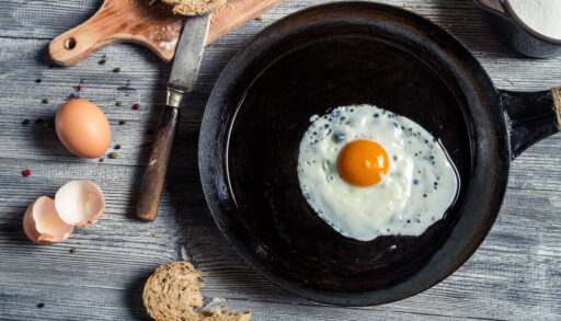 Overhead view of a fried egg in a black cast iron pan.