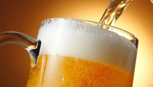 Close-up of the top of a beer glass being filled with beer.