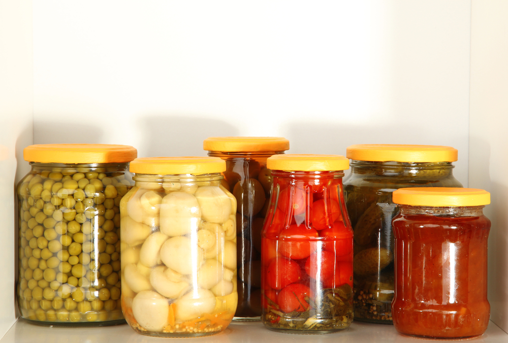 Glass jars filled with different canned vegetables.