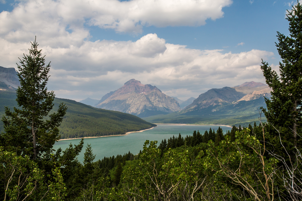 View of a blue lake surrounded by trees and mountains in Waterton-Glacier International Peace Park.