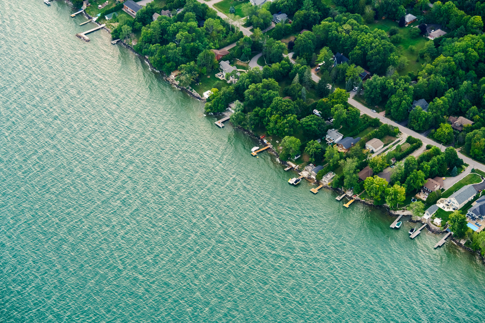 Aerial view of a blue Lake Ontario with houses along the shoreline.