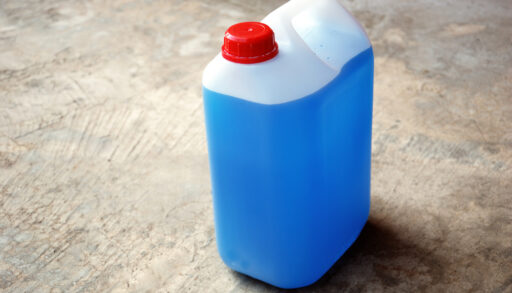 Bottle of blue antifreeze on a concrete floor.