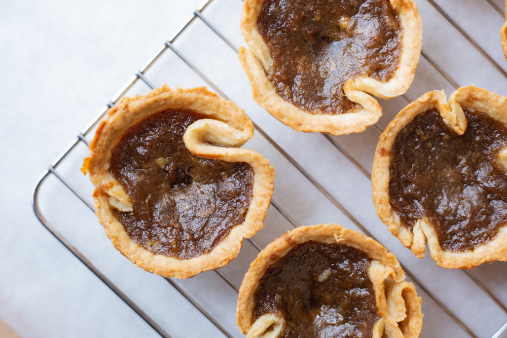 Overhead view of butter tarts on a metal cooling rack.
