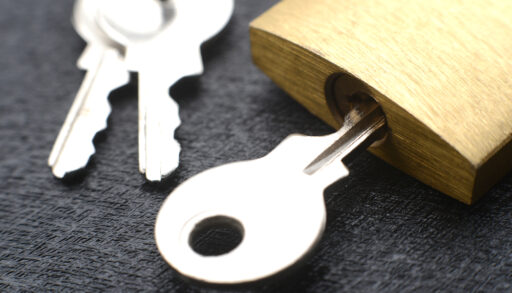 Silver key in a small gold padlock.