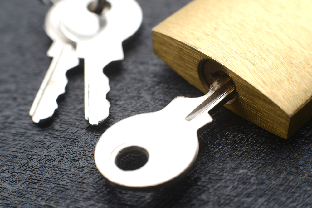 Silver key in a small gold padlock.