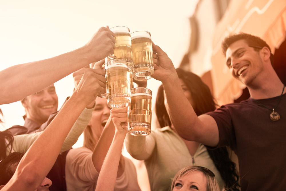 Group of people smiling and raising beer glasses.