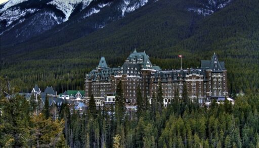 Banff Springs Hotel next to a mountain surrounded by trees.