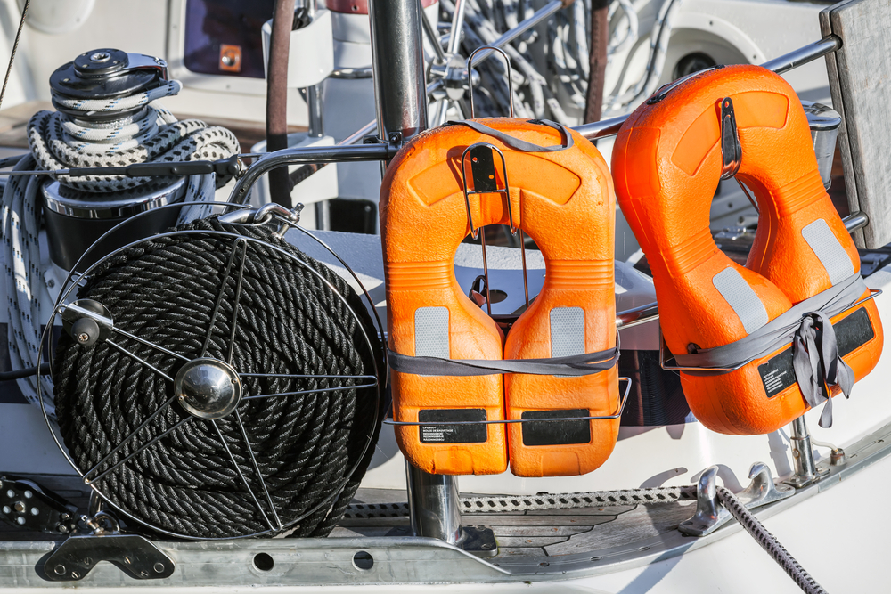 Orange life jackets and a coil of black rope on the back of a boat.