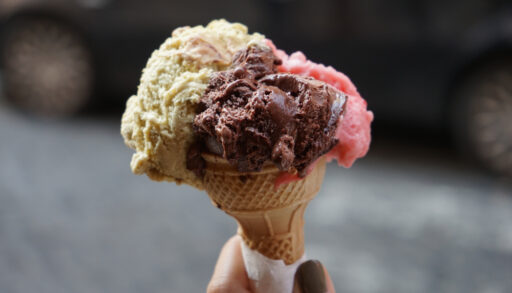 Woman holding an ice cream cone with vanilla, chocolate and strawberry ice cream.