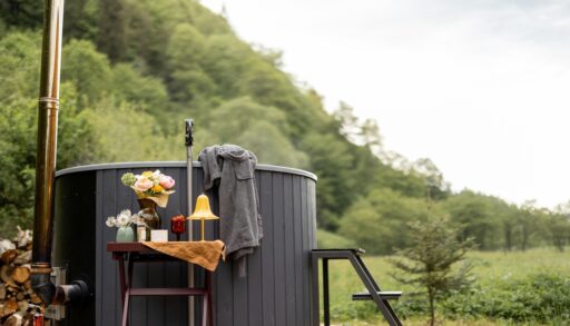 Small, grey hot tub on a wooden deck surrounded by trees.