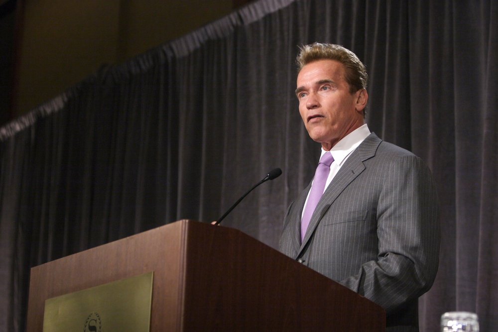 Arnold Schwarzenegger speaking behind a podium.