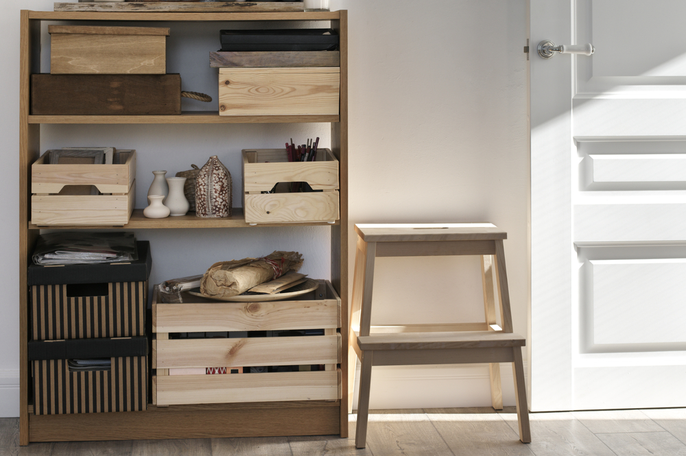 Wooden shelf with wooden crates next to a wooden step stool.