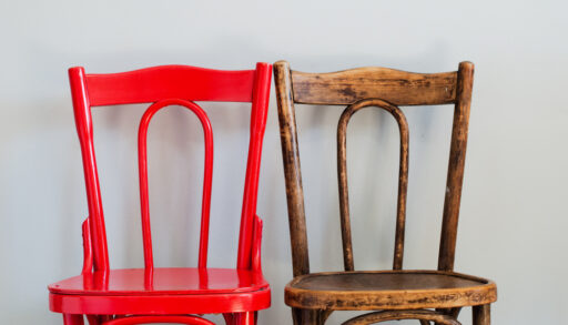 Old, wooden chair next to a newly-painted, bright red version of the same chair.