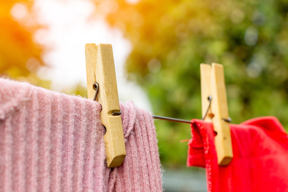 Close-up of clothes-pins holding clothing on an outdoor clothesline.