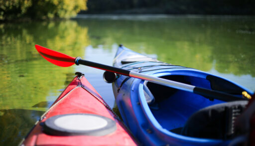 Close-up of red and blue kayaks on a lake.