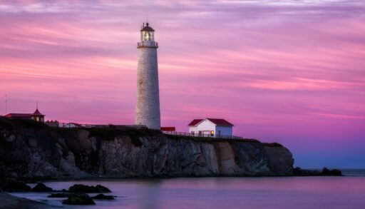 Pink and purple sunset behind the Cap-des-Rosiers Lighthouse in Forillon National Park, Gaspesie, Quebec, Canada.