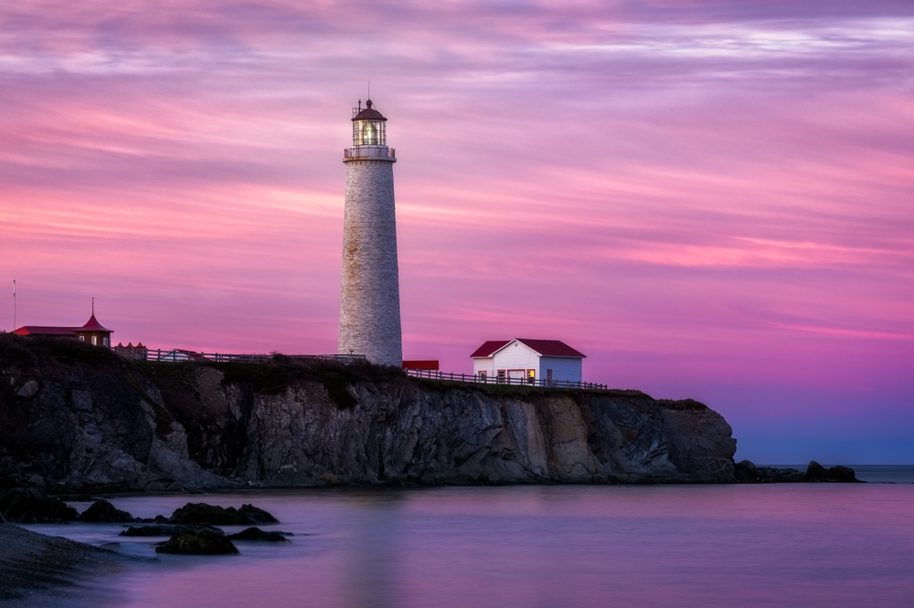 Pink and purple sunset behind the Cap-des-Rosiers Lighthouse in Forillon National Park, Gaspesie, Quebec, Canada.
