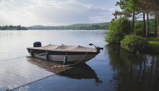 Motor boat anchored to a dock on a lake.