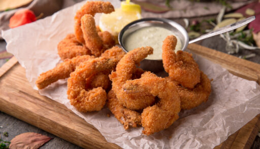 Close-up of deep-fried shrimp next to a dipping sauce.