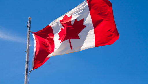 Canadian flag waving against a blue sky.