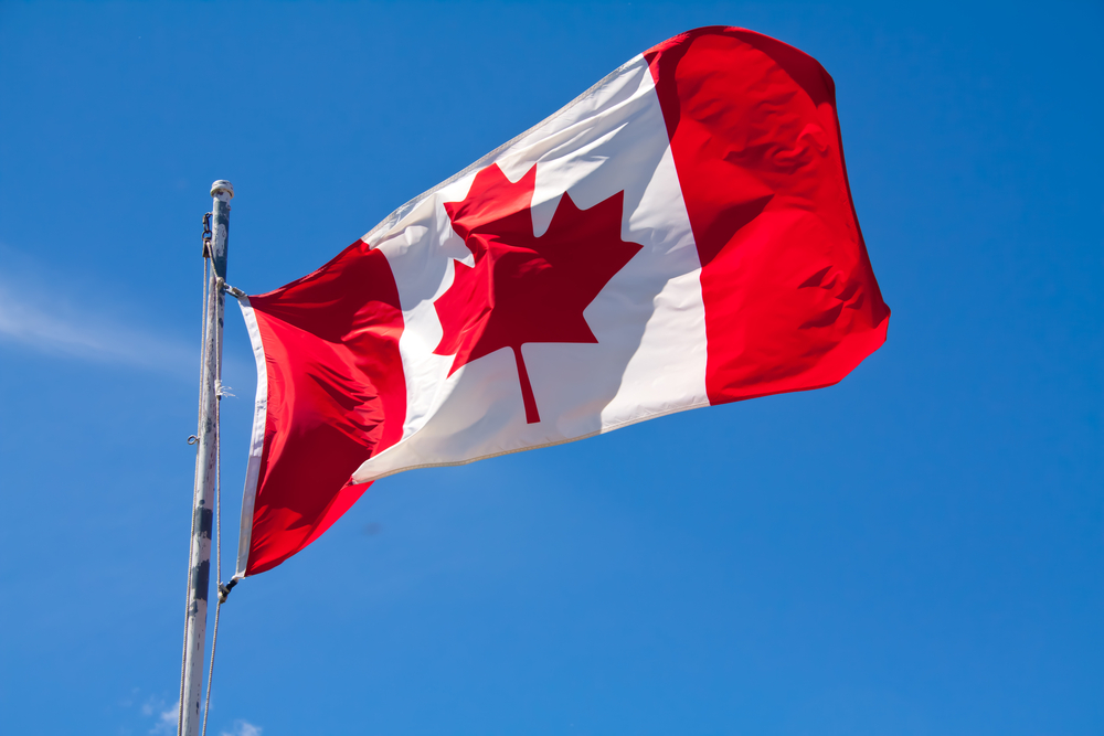 Canadian flag waving against a blue sky.