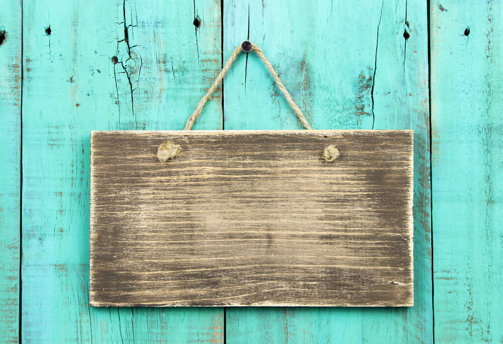 Blank wooden sign on a turquoise wood background.