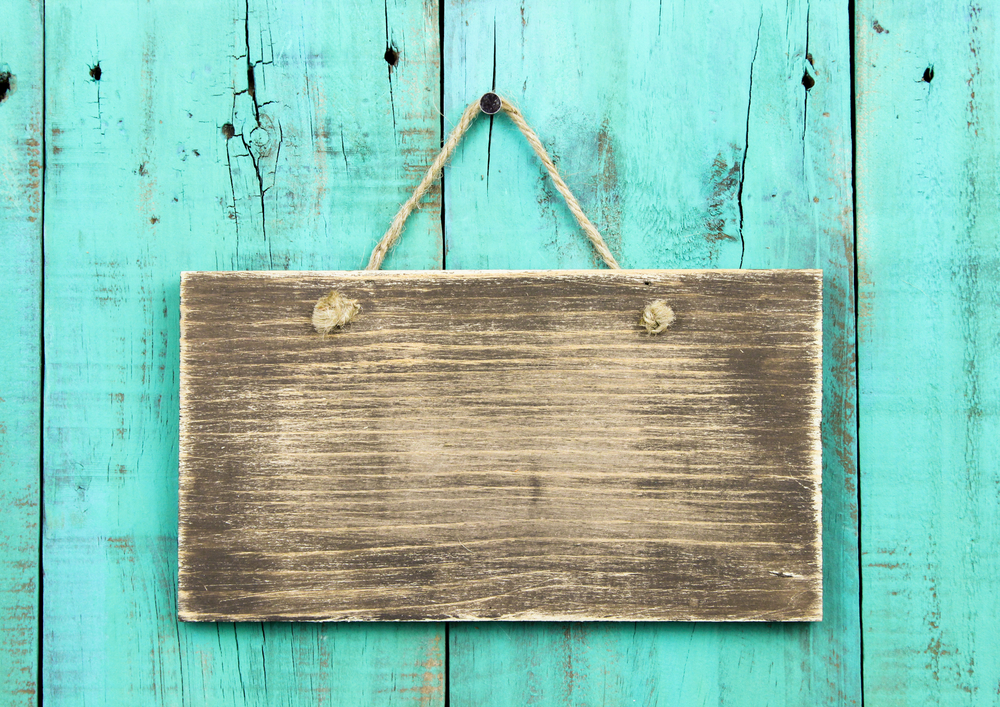 Blank wooden sign on a turquoise wood background.