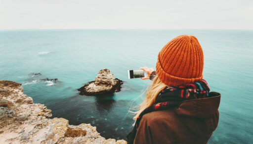 Woman in an orange hat taking a photo with her smartphone.