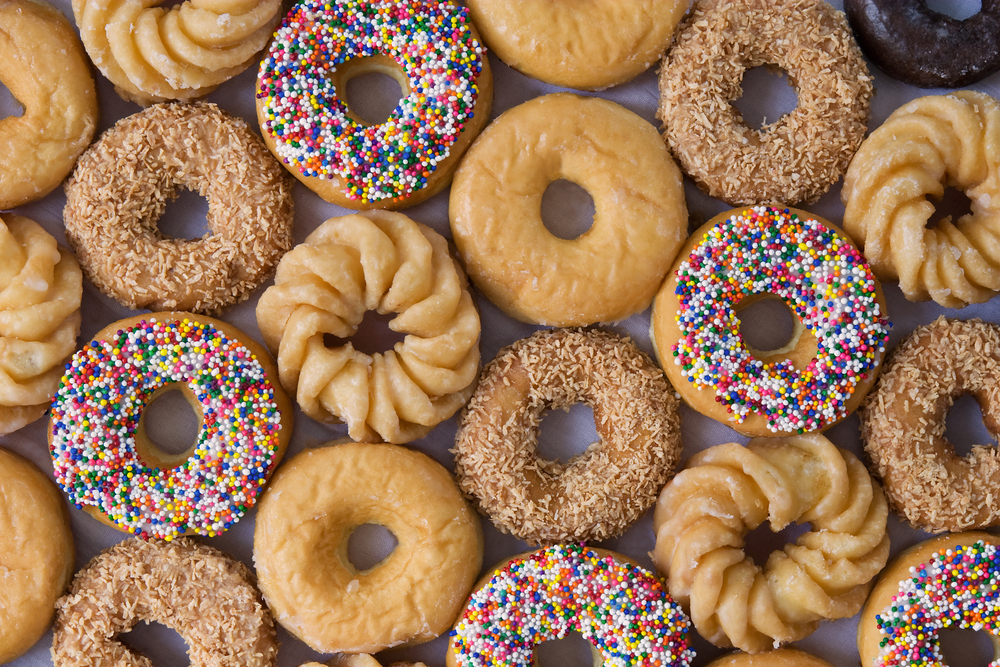 Overhead view of rows of different types of donuts.