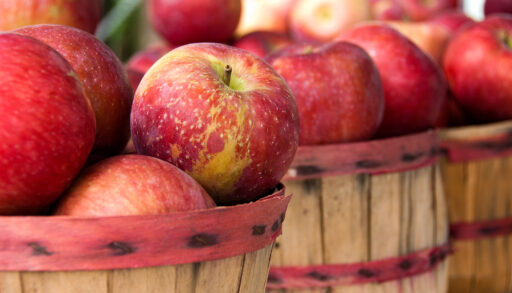 Close-up of red apples stacked in barrels at a farmers' market.