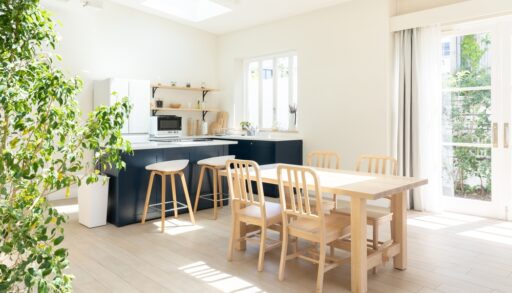 Kitchen interior with bright walls, blue cabinets and a wooden dining table.