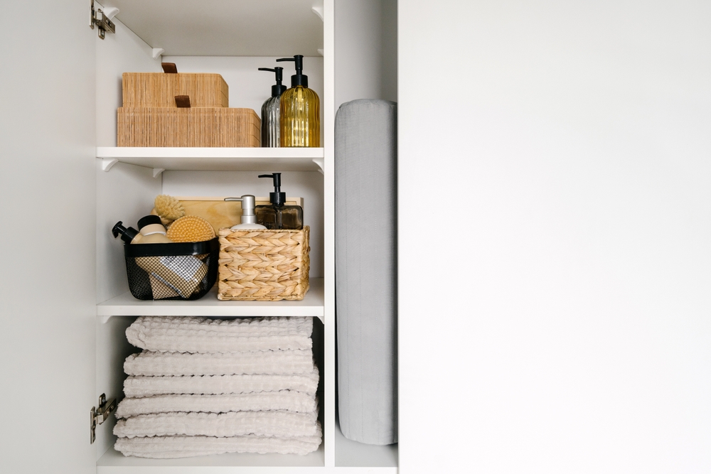 Close-up of a bathroom cabinet with folded towels and soap bottles.